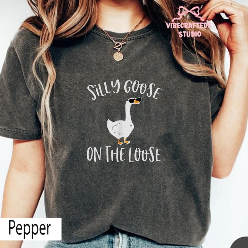 May include: A dark gray t-shirt with the text "Silly Goose On The Loose" and a cartoon goose wearing sunglasses. The shirt also has the word "Pepper" at the bottom.
