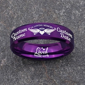May include: A purple ring with engraved text and a heart with wings design. The ring features the words "Custom Name" and "Custom Date", with "In Loving Memory" and "Loved beyond words" also inscribed.