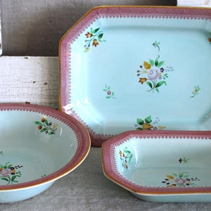 May include: Three vintage ceramic dishes with a light blue background and floral designs in pink, yellow, and green. The dishes have a pink and white trim.