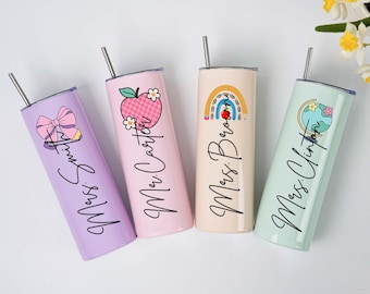 以下が含まれることがあります： 蓋とストローが付いた4つのステンレス鋼タンブラー。それぞれ異なるデザインと名前が特徴です。タンブラーはパステルカラーで、ラベンダー、ピンク、ベージュ、ミントグリーンです。デザインには、リボン、リンゴ、虹、地球が含まれています。
