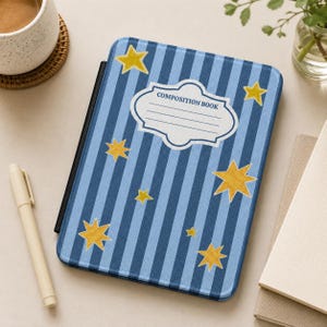 May include: A blue composition book cover with vertical stripes and gold stars. The cover features a white label with the words "COMPOSITION BOOK" and lines for writing. The book is open, revealing black edges.
