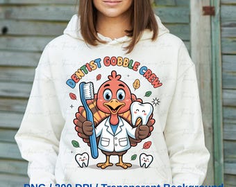 May include: A white hooded sweatshirt featuring a colorful cartoon turkey dressed as a dentist, holding a toothbrush and a tooth. The text "DENTIST GOBBLE CREW" is arched above the turkey. Additional graphics include leaves and teeth.