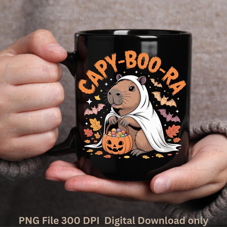 May include: Black ceramic mug featuring a Halloween-themed design. The mug displays a capybara dressed as a ghost, holding a pumpkin basket. The text "CAPY-BOO-RA" is arched above the capybara. Bats and autumn leaves complete the design.