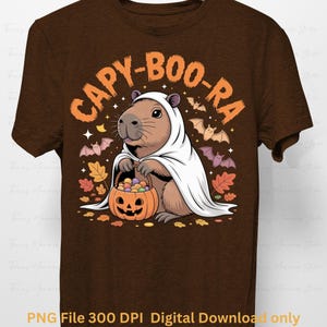 May include: Brown t-shirt featuring a capybara dressed as a ghost, holding a pumpkin basket filled with candy. The shirt has the text "CAPY-BOO-RA" in orange, with bats and autumn leaves. The bottom of the shirt reads "PNG File 300 DPI Digital Download only".
