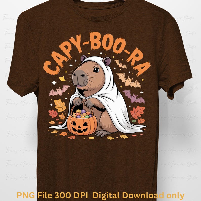 May include: Brown t-shirt featuring a capybara dressed as a ghost, holding a pumpkin basket filled with candy. The shirt has the text "CAPY-BOO-RA" in orange, with bats and autumn leaves. The bottom of the shirt reads "PNG File 300 DPI Digital Download only".
