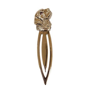 Könnte beinhalten: Goldfarbener Metall-Lesezeichen mit einem detaillierten, dreidimensionalen Labrador-Kopf mit roten Augen. Das Lesezeichen hat ein schlichtes, elegantes Design mit einer doppelfachen Klammer.