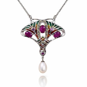 Puede incluir: Collar con colgante plateado con un diseño en forma de abanico. El colgante presenta piedras preciosas rojas, detalles de marcasita y detalles de esmalte colorido en verde, rojo y amarillo. Una perla blanca cuelga de la parte inferior.