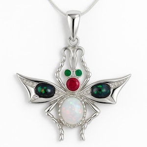 Op de afbeelding: Een zilveren hanger ketting met een gestileerd insectenontwerp. De hanger heeft een centrale ovale opaal, een rode robijn en groene smaragd accenten. De vleugels hebben zwarte opaal stenen en kleine heldere kristallen.