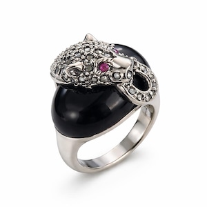 May include: A silver ring with a panther head design. The panther head is adorned with small, clear stones and two small red stones for eyes. The ring features a large, black, oval-shaped stone as the panther's body.