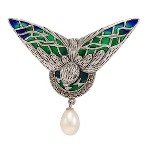 May include: A silver butterfly brooch with green and blue enamel wings. The brooch has a central floral design and a dangling white pearl. The wings have a detailed, openwork design.