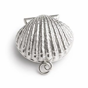 May include: A silver seashell-shaped clasp for jewellery. The clasp has a detailed, ridged surface and a small loop at the bottom. The clasp is designed to secure jewellery pieces.