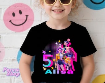 May include: Black t-shirt featuring a colorful graphic design with the number 5, stars, and the name "Alisa". The design includes images of animated characters. The shirt is worn by a child.