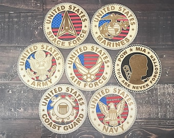 May include: A set of wooden coasters displaying the emblems of the US military branches and Space Force. Each circular coaster has the words "United States" and the branch name. The coasters are in shades of brown, red, blue, and gold, with a diameter of approximately 10 cm.