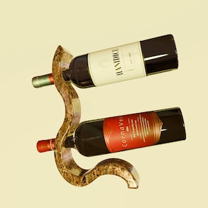 May include: A brown marble wine rack with two bottles of wine. The top bottle is labelled "HANDDICE" and the bottom bottle is labelled "cornaveil".