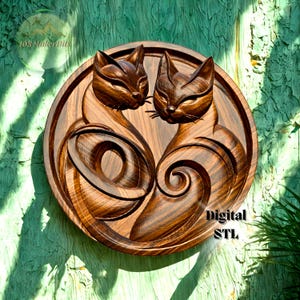 以下が含まれることがあります： 丸い木製の壁掛けアートで、2匹の様式化された猫の顔が向かい合っています。 猫は詳細に彫刻されており、渦巻く模様と濃い茶色の仕上げが施されています。 「Digital STL」というテキストが表示されています。