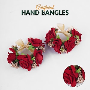 May include: Two artificial hand bangles with red roses, green leaves, and gold accents. Each bangle features a cream-colored ribbon bow. The text "Artificial HAND BANGLES" is at the top.