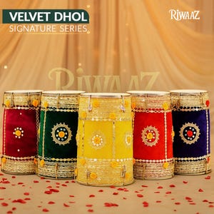 Op de afbeelding: Vijf kleurrijke fluwelen dhol-drums met gouden afwerking en decoratieve accenten. De drums zijn in tinten rood, groen, geel en blauw. De tekst "VELVET DHOL SIGNATURE SERIES" staat bovenaan.