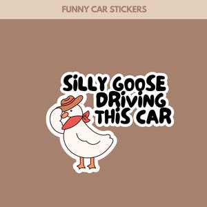 Op de afbeelding: Een witte sticker met een cartoon gans met een cowboyhoed en een rode bandana. De tekst "SILLY GOOSE DRIVING THIS CAR" is in zwart en wit. De sticker staat op een bruine achtergrond, met de woorden "FUNNY CAR STICKERS" bovenaan.