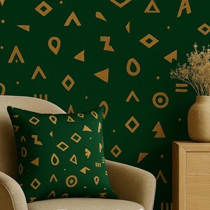 Könnte beinhalten: Ein grünes Zierkissen mit goldenen geometrischen Formen, das auf einem beigen Stuhl liegt. Die Wand dahinter ist grün mit goldenen Formen. Der Text "Forest Code" ist sichtbar.