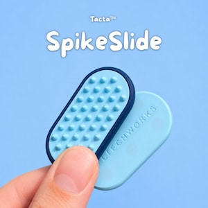 Peut inclure: Un outil de manipulation tactile ovale bleu clair avec une bordure bleu foncé et une surface texturée comportant de petits picots en relief. L'objet porte le texte Tacta SpikeSlide et le mot LITECHWORKS gravé sur la face lisse.
