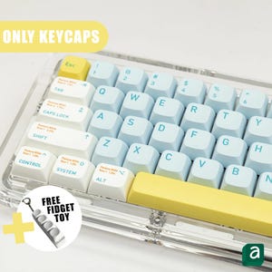 May include: A keyboard with light blue and white keycaps, with yellow accent keys. The image includes the text "ONLY KEYCAPS" and "FREE FIDGET TOY". The keyboard is in a clear case.