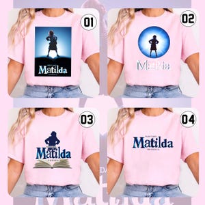 May include: Four light pink t-shirts with designs from the musical "Matilda." Each shirt displays a different graphic: a silhouette, a stage scene, and the musical's logo. The t-shirts are short-sleeved and made of a soft material.