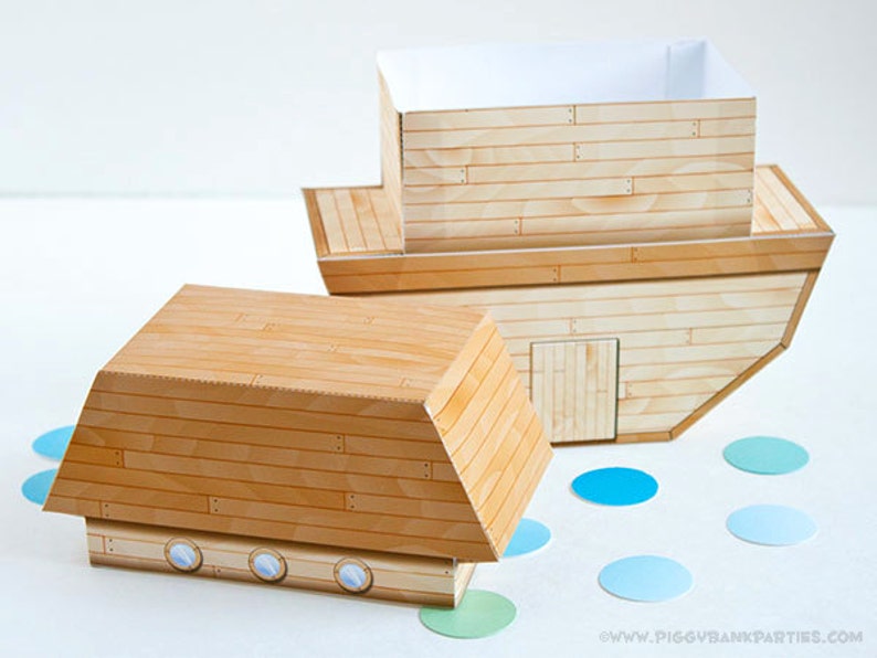 May include: Two wooden toy boats with a light wood grain pattern. One boat is upright, showing the interior, and the other is on its side. Blue and green confetti dots are scattered around the boats.