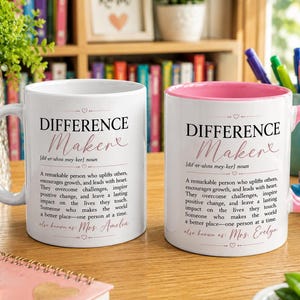 Könnte beinhalten: Zwei weiße Keramikbecher mit rosa Innenseite und Henkel. Jeder Becher zeigt den Text 'DIFFERENCE Maker' in schwarzer und rosa Schrift, gefolgt von einer wörterbuchartigen Definition eines 'Difference Maker' und einem Namen am unteren Rand.