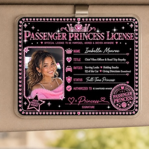May include: A rectangular black car visor accessory titled Passenger Princess License with pink glitter accents. It features a photo of a person, text fields for name, title, duties, status, and a circular seal reading Officially Certified Passenger Princess.