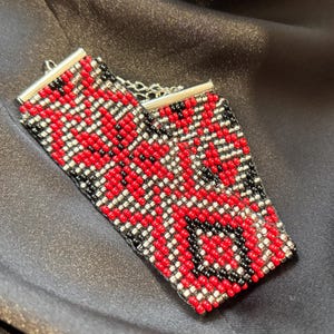 Könnte beinhalten: Zwei Perlenarmbänder mit einem geometrischen Muster in Rot, Schwarz und Silber.