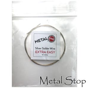 May include: A package containing silver solder wire. The label reads "METAL STOP" with the text "Silver Solder Wire EXTRA EASY 12 inches". The wire is coiled inside a clear plastic bag, with the brand name printed at the bottom.