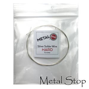May include: A clear plastic bag containing a coil of silver solder wire. A white label reads "METAL STOP" and "Silver Solder Wire HARD 12 inches."