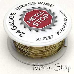Może przedstawiać: Szpula drutu mosiężnego o grubości 24 gauge, o długości 15,24 metra, z etykietą "Metal Stop Premium Quality Brass Wire". Szpula jest biała z czerwonym znakiem stop, na którym widnieje napis "Metal Stop".