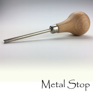 May include: A metal tool with a wooden handle and a silver-colored shaft. The handle is a light brown color and bulbous in shape. The text "Metal Stop" is written in a cursive font at the bottom of the image.