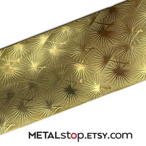 May include: A close-up of a gold-coloured metal sheet featuring a repeating starburst design. The surface has a textured finish, with the starbursts slightly raised. The text "METALstop.ETSY.com" is visible in the lower right corner.