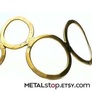 May include: A gold-colored metal headband with an abstract design. The headband features a series of interconnected circular and oval shapes. The surface has a slightly aged appearance. The Etsy shop name "METALstop.ETSY.com" is visible at the bottom.