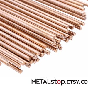 Pode incluir: Um conjunto de varetas met&aacute;licas de cor cobre, dispostas diagonalmente sobre um fundo branco. As varetas s&atilde;o cil&iacute;ndricas e parecem ter um comprimento uniforme. O texto "METALstop.ETSY.com" &eacute; vis&iacute;vel na parte inferior.
