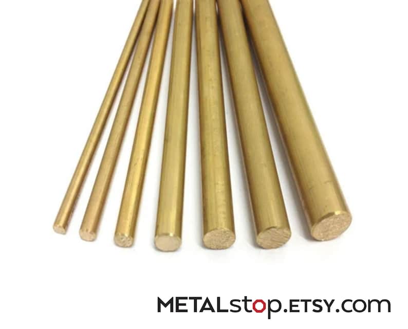 Pode incluir: Uma cole&ccedil;&atilde;o de varetas de lat&atilde;o de v&aacute;rios di&acirc;metros, dispostas sobre um fundo branco. As varetas t&ecirc;m um tom dourado e s&atilde;o cil&iacute;ndricas. O texto "METALstop.ETSY.com" &eacute; vis&iacute;vel na parte inferior.