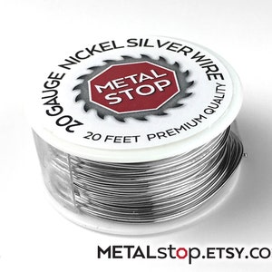 Könnte beinhalten: Eine Spule mit 20 Gauge Nickelsilberdraht, beschriftet mit "METAL STOP" und 6,1 Metern Draht. Die Spule hat eine weiße Oberseite mit schwarzem Text und einem rot-weißen Logo. Der Draht ist silberfarben und eng gewickelt.
