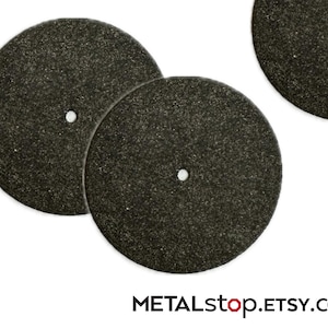 Può includere: Primo piano di diverse mole abrasive grigio scuro con un foro centrale. Le mole hanno una superficie strutturata e sono disposte su uno sfondo bianco. Il nome del negozio Etsy METALstop.ETSY.com è in basso.