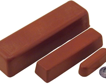 Pode incluir: Três barras retangulares marrons de composto de polimento em tamanhos variados, com uma moeda para escala. As barras são de cor sólida e uniforme e têm bordas arredondadas. A barra maior tem cerca de 15 cm de comprimento.
