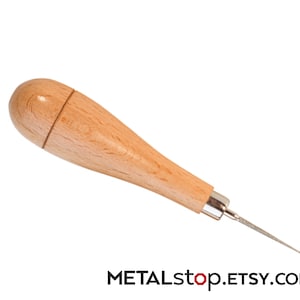 May include: A wooden awl with a light brown handle and a silver metal ferrule. The awl has a pointed, textured metal tip. The text "METALstop.ETSY.com" is at the bottom.
