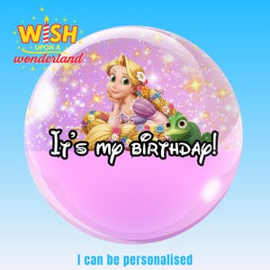 Op de afbeelding: Een roze en heldere bel met een cartoonafbeelding van een prinses met lang blond haar en een groene kameleon. De tekst "It's my birthday!" staat onderaan. De woorden "Wish Upon a Wonderland" staan bovenaan.