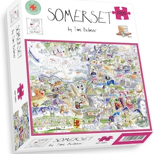 May include: A boxed 1000-piece jigsaw puzzle depicting a detailed, illustrated map of Somerset, England, by Tim Bulmer. The puzzle box displays the word "SOMERSET" and various illustrations of local landmarks and cultural references.