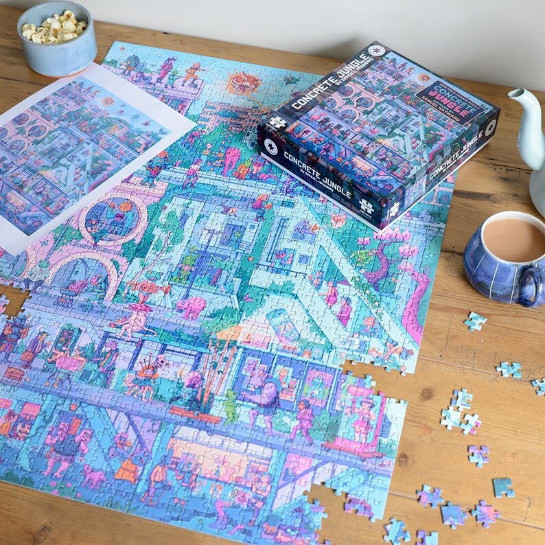 May include: A partially assembled jigsaw puzzle with a colorful cityscape design, titled "Concrete Jungle." The puzzle is on a wooden surface, with the box and a print of the image visible. A cup of tea and popcorn are also present.