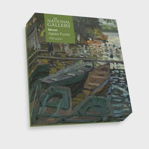 Può includere: Un puzzle in scatola con un dipinto di barche su uno specchio d'acqua. La scatola ha un'etichetta verde che recita "The National Gallery Monet Jigsaw Puzzle 1000 pieces."