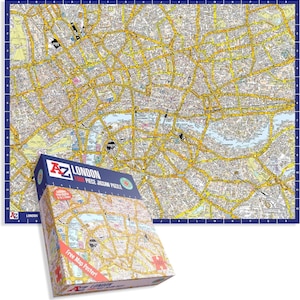 May include: A London map jigsaw puzzle with a blue border, alongside its box. The box reads "A-Z London 1000 Piece Jigsaw Puzzle" and "Free Map Poster!" The map shows the city's streets and landmarks in detail.