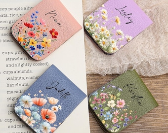 May include: Four magnetic bookmarks with floral designs and personalized names: Nina, Lesley, Judith, and Kristin. The bookmarks are in pink, lilac, blue, and green, with flower illustrations. Each bookmark is approximately 5 cm wide.