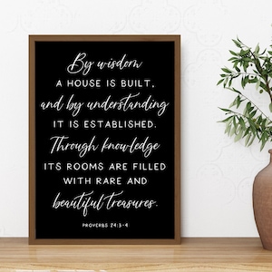 May include: A framed black and white print with inspirational text. The text reads "By wisdom a house is built, and by understanding it is established. Through knowledge its rooms are filled with rare and beautiful treasures." A vase with greenery is to the right.