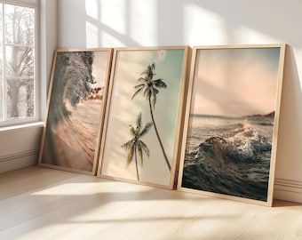 May include: Three framed art prints leaning against a wall. The prints feature ocean waves and palm trees, with a warm color palette of beige, brown, and blue. The frames are a light wood color.
